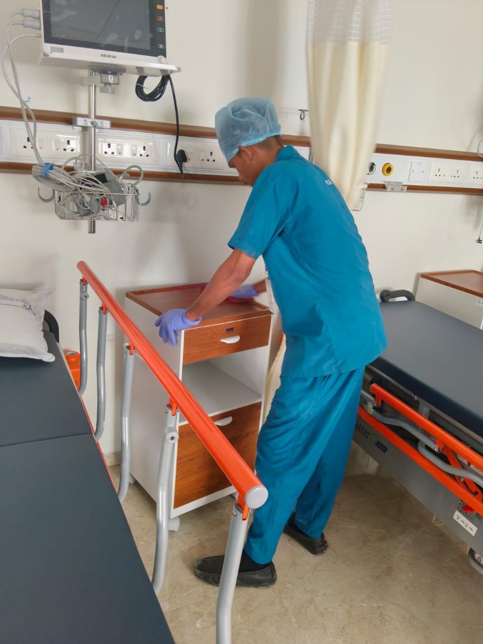 Staff managing hospital linen and bedside furniture